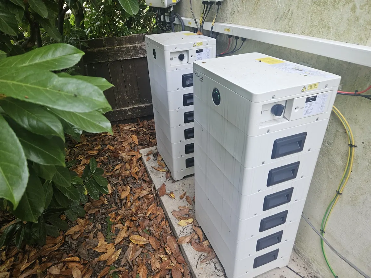 Modular battery storage units positioned beside an anonymised residential building
